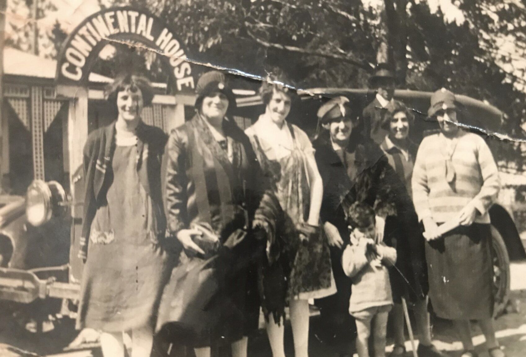 A group of women and a child in 1920s dress beneath the Continental House arch