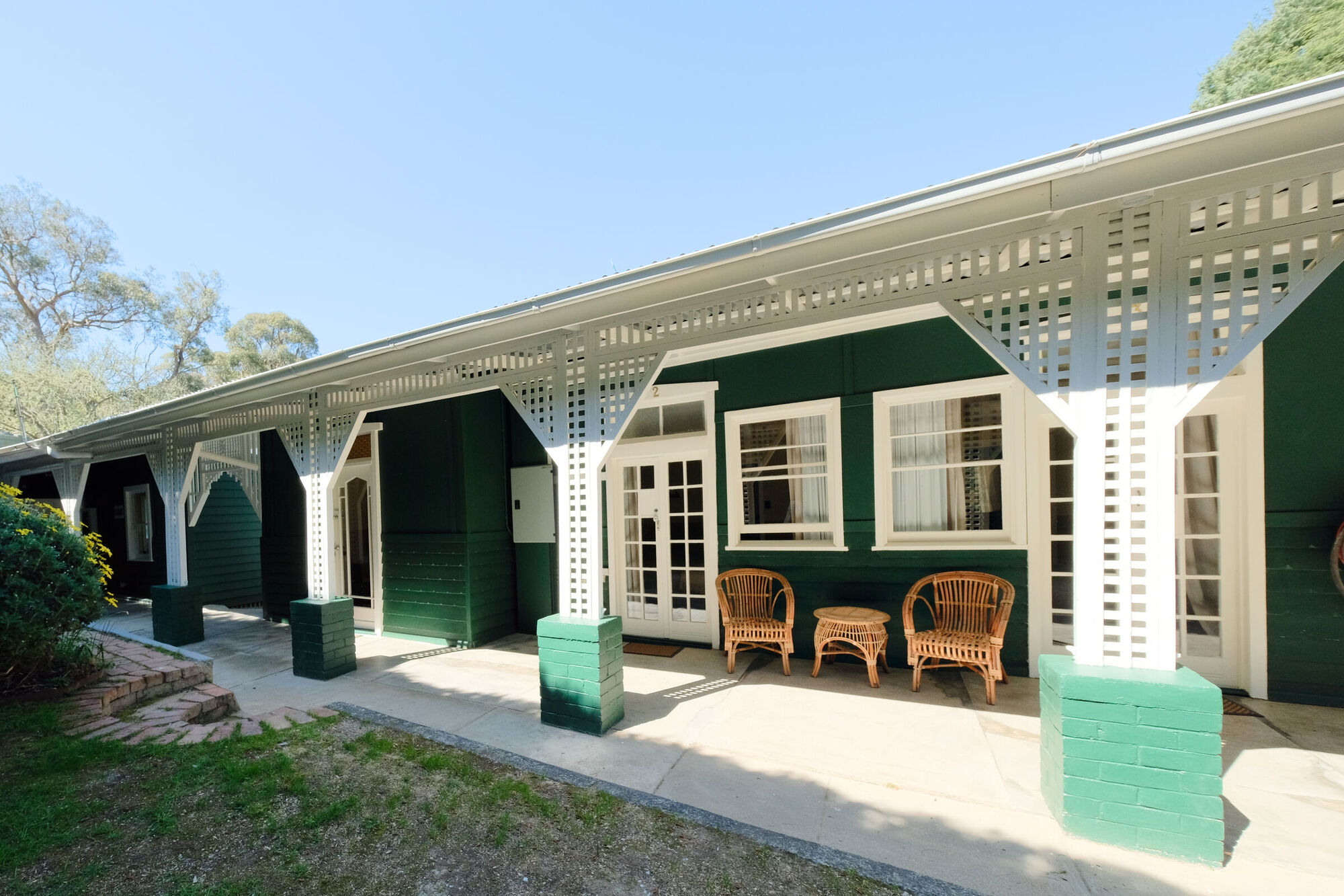 The green weatherboard facade of Continental House with its white lattice verandah