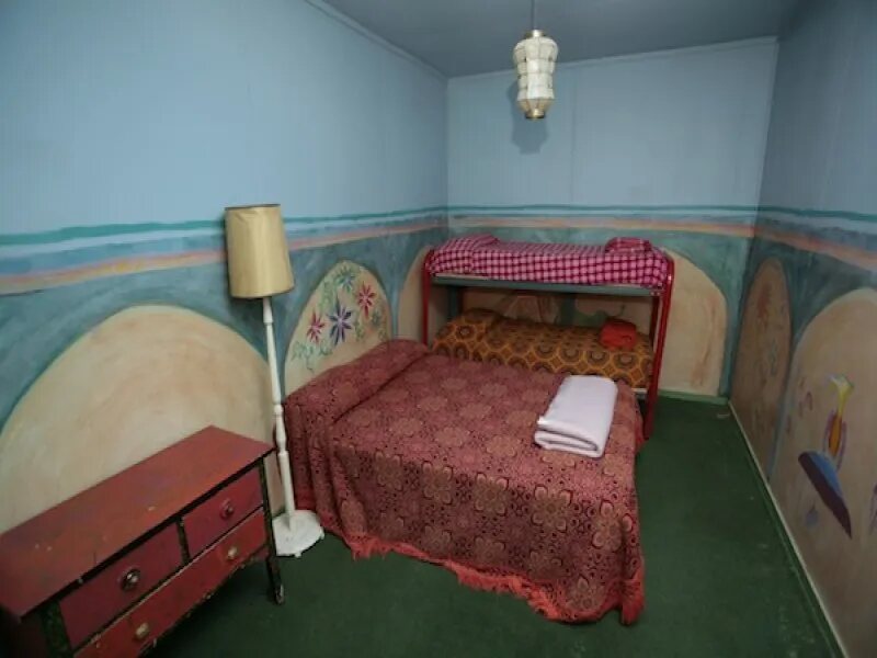 A bedroom with painted walls and a red bedspread